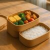 二段弁当箱にご飯を下段、おかずを上段に美しく詰めた理想的な配置のイメージ。